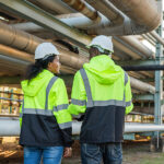 Two workers inspect Swagelok quick connect fittings on industrial pipelines.